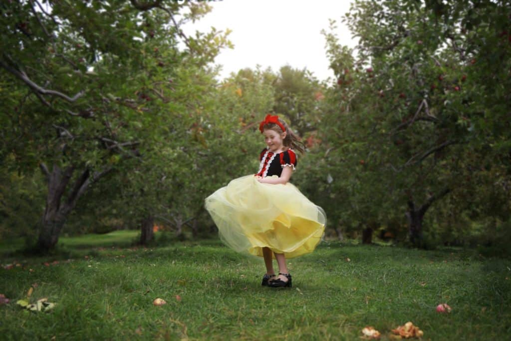 little girl dressed up as snow white twirling around in apple orchard