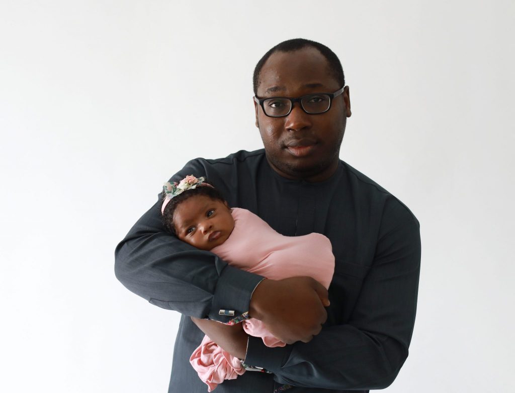 dad holding newborn daughter looking at the camera
