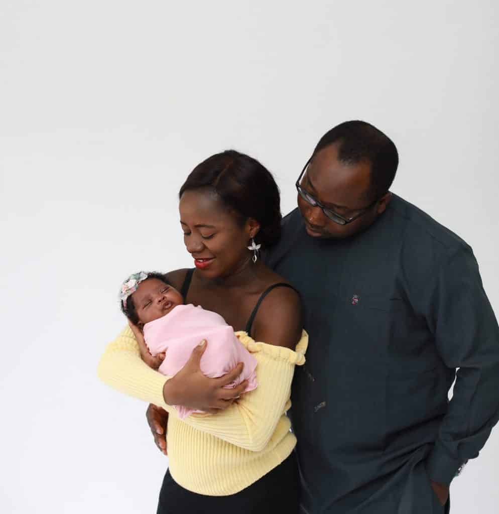 dad holding his wife, mother holding newborn daughter, both looking at newborn