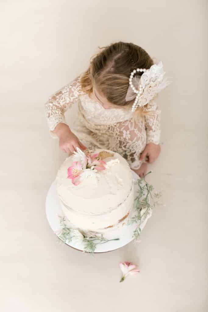 one year old girl looking down at her eaten cake 
