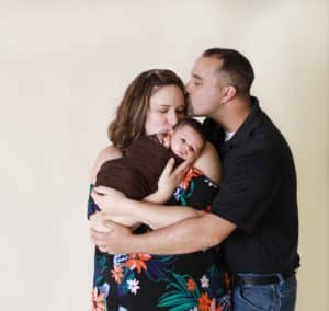 new mother and father kissing newborn baby in Auburn Maine studio