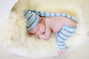 baby boy laying in a moon in blue clothes with lots of wrinkles