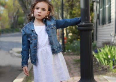 Portland Maine Portrait Photographer, girl in white dress and blue jean jacket swinging around light pole