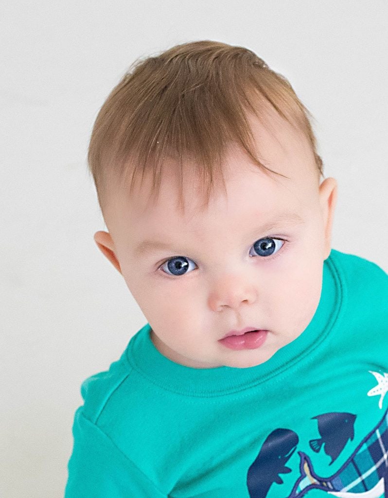 One year old looking at the camera in blue shirt