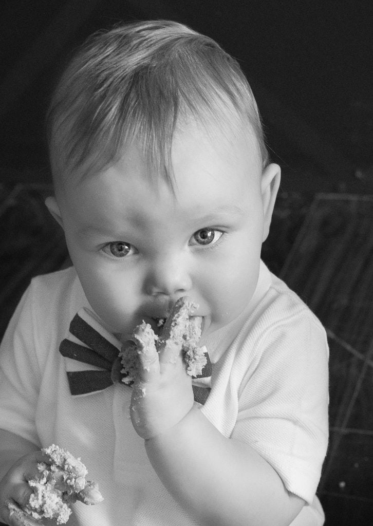 One year old trying his cake from cake smash, photo in black and white.