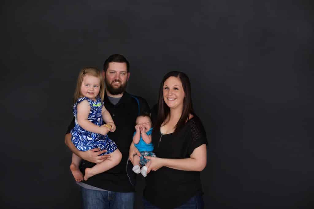 Family photo session. Black background, mom, dad, baby, toddler girl