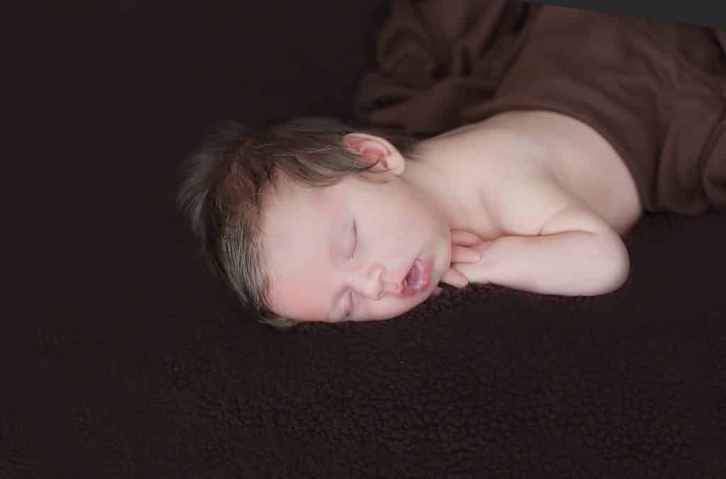 newborn photo session, sleeping, black background, brown wrap from waist down, sleeping on belly
