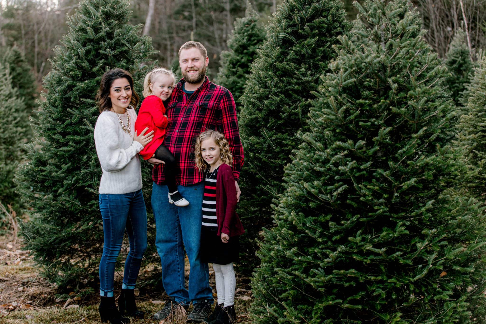 mom,dad, two girls in the christmas tree farm