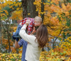 mother holder her toddler son up in the air. Fall family photo