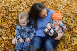 mom and her boys playing in the fall leaves 