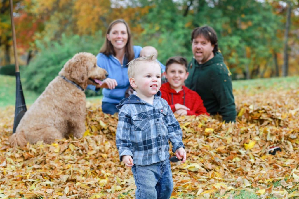 family in the fall leaves with their family dog