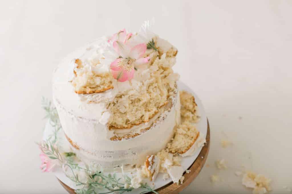 botanical themed white cake that has been eaten by the one year old girl