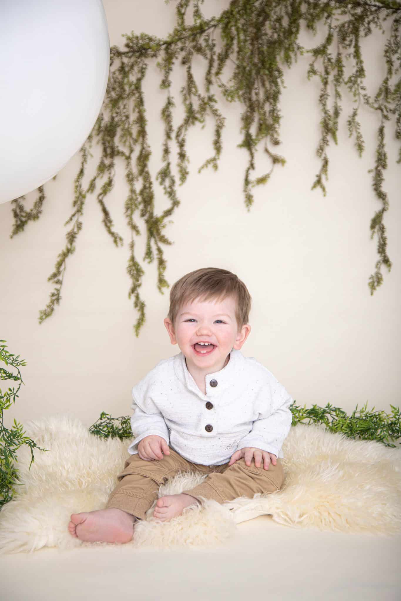 One year boy photos. big white balloon, green garland, white fur