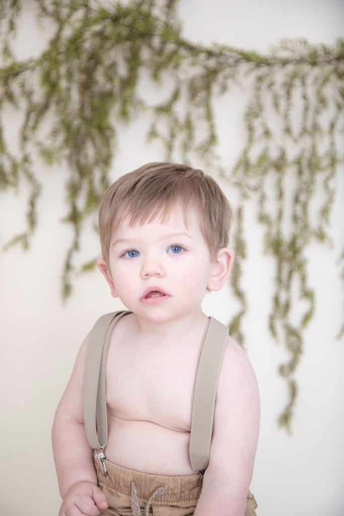 One year boy wearing suspenders with blue eyes, green galrdand