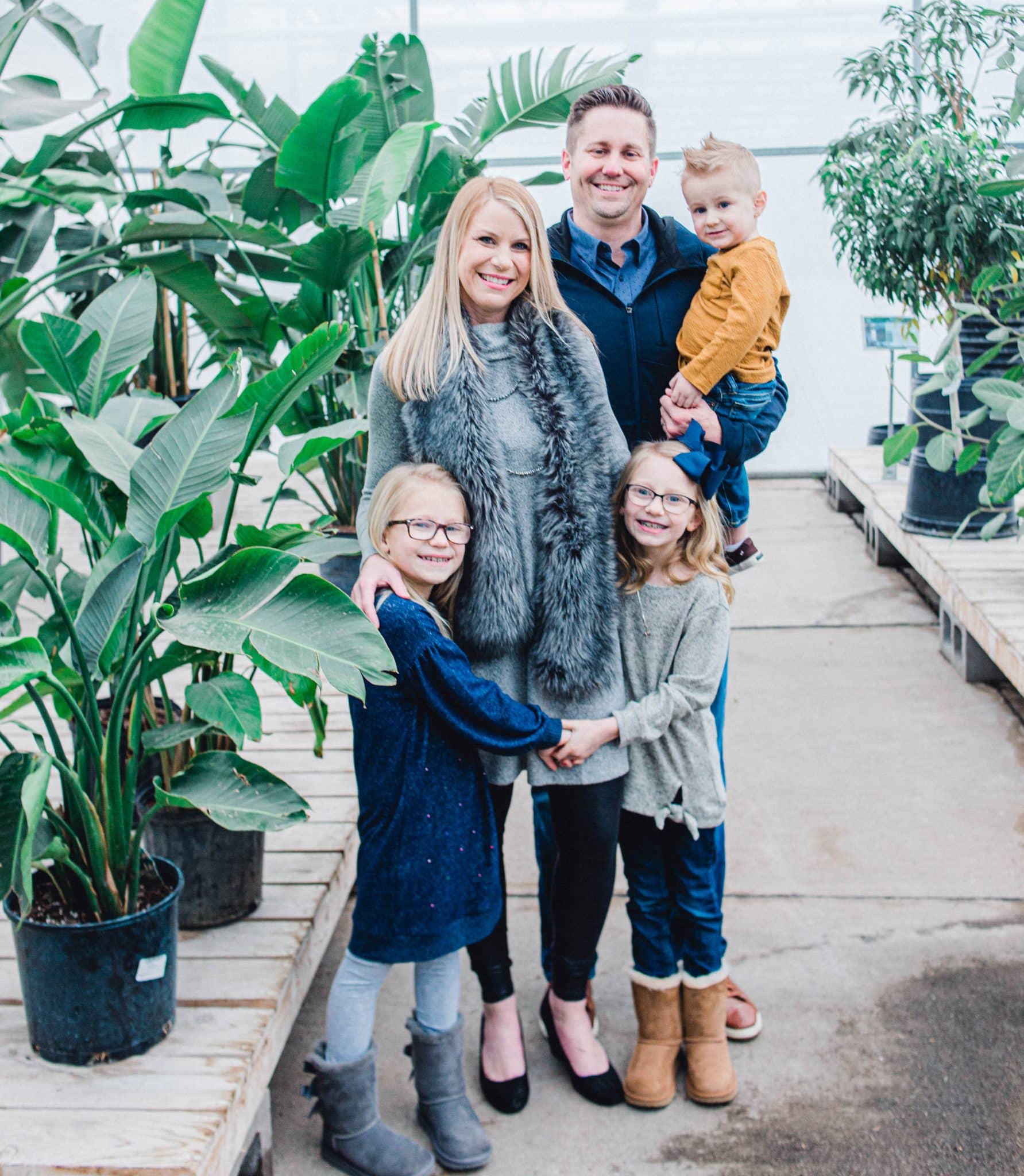 family of 5 looking at camera, in greenhouse