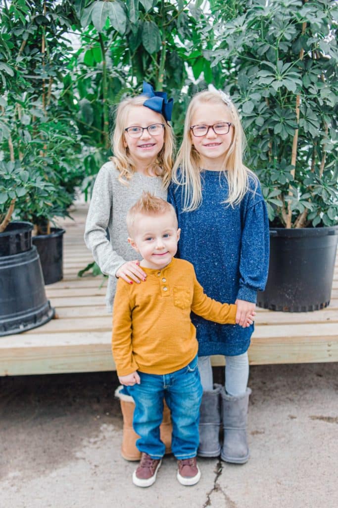 two girls and one boy holding hands looking at the camera