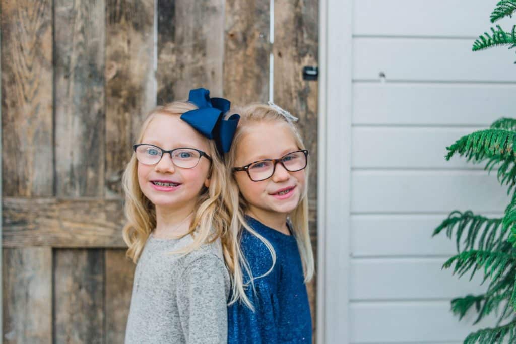 sisters back-to-back looking at the camera in front of a barn door