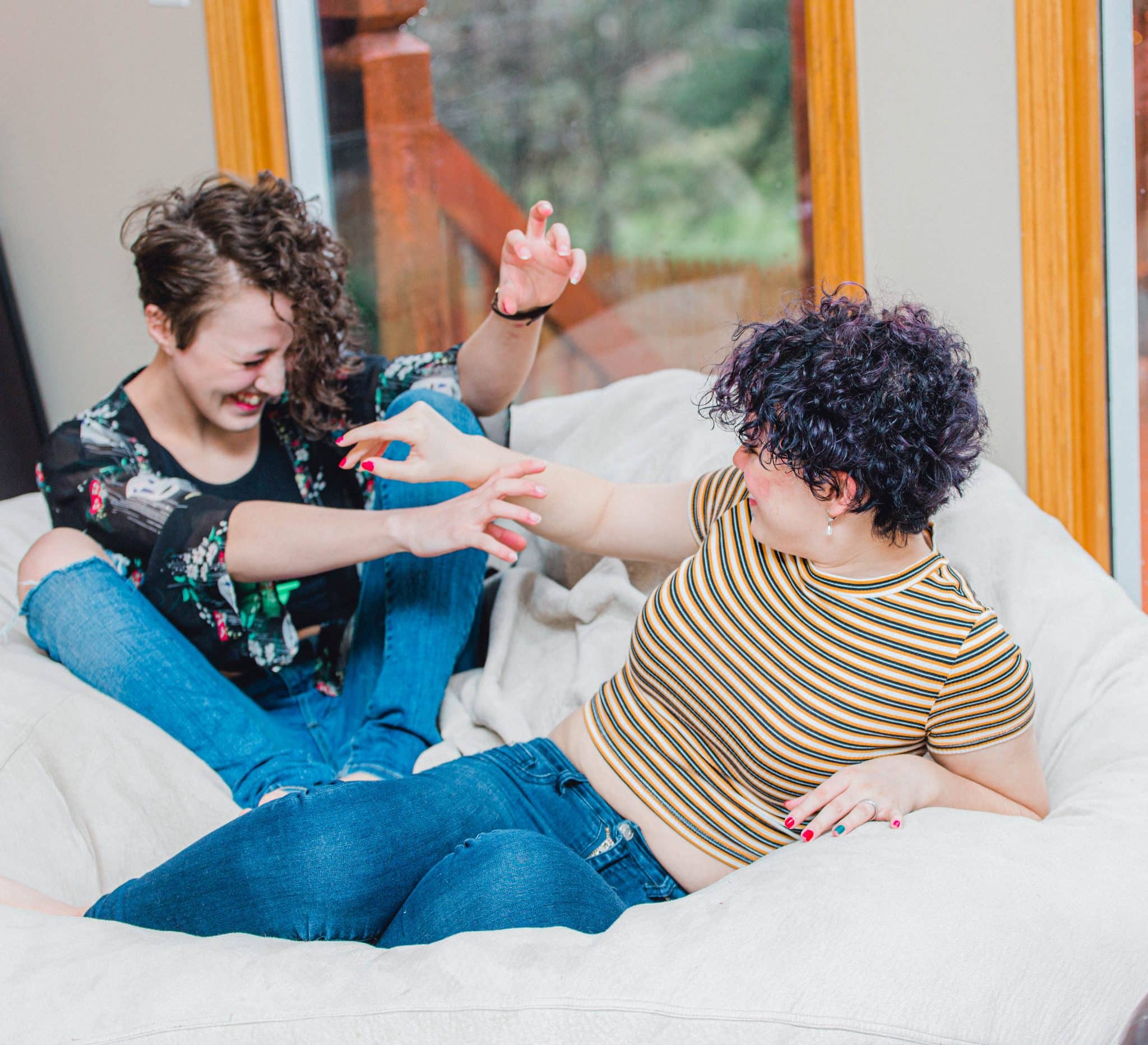 two teenage girls sitting on a bean bag laughing