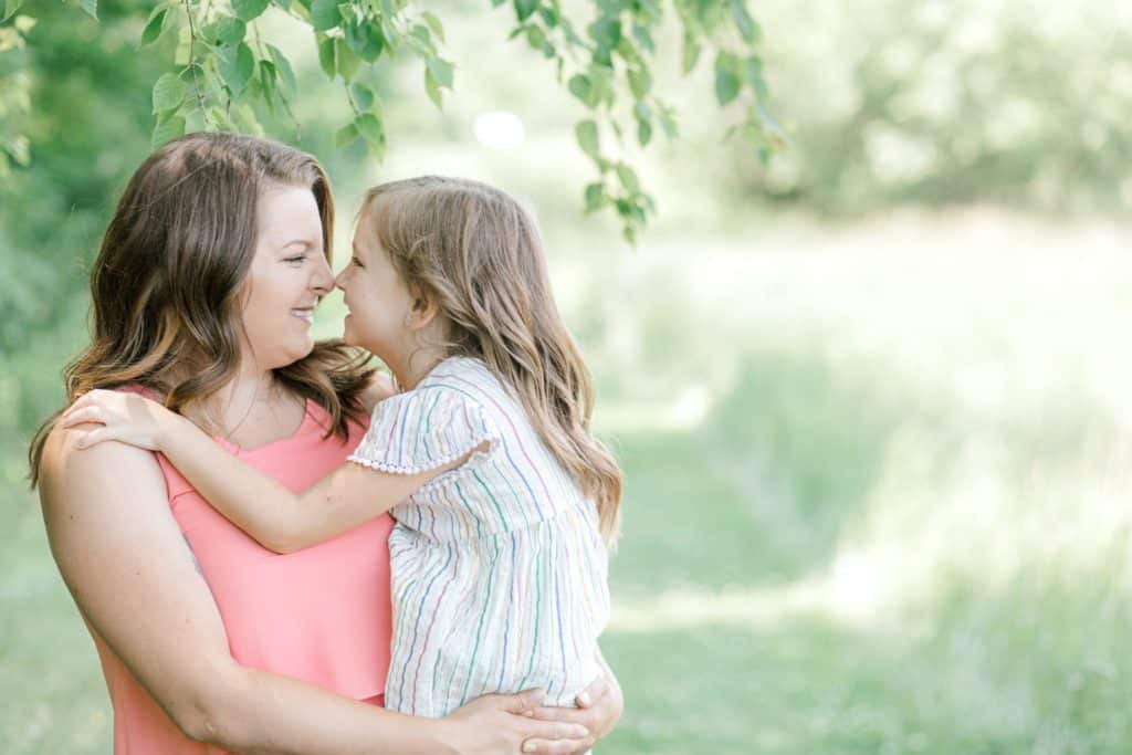 mother holding daughter touching noses