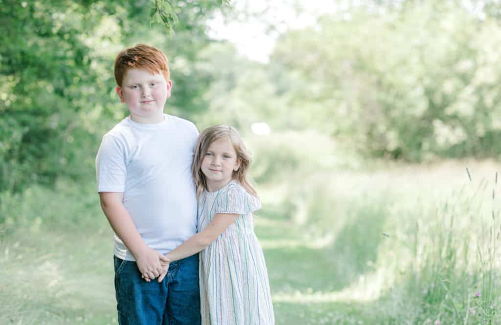 brother and sister holding hands, looking at the camera