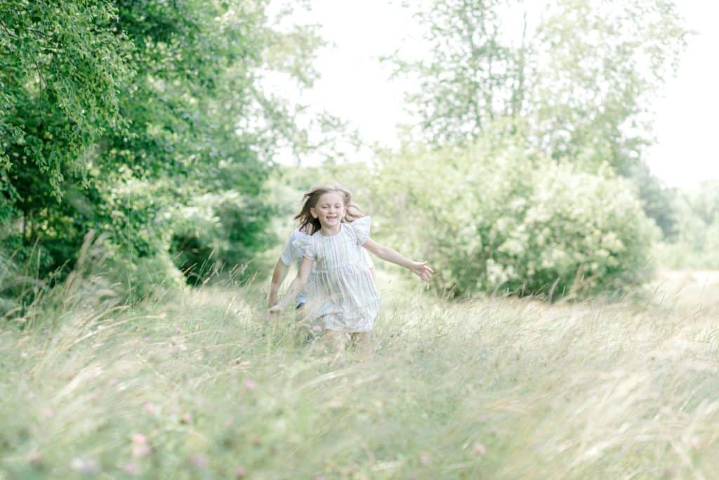 little girl running towards the camera in the tall grass