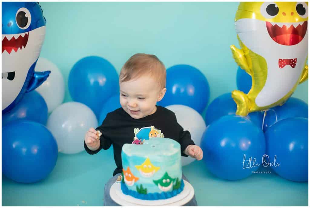 baby eating cake at one year cake smash session with baby shark cake 