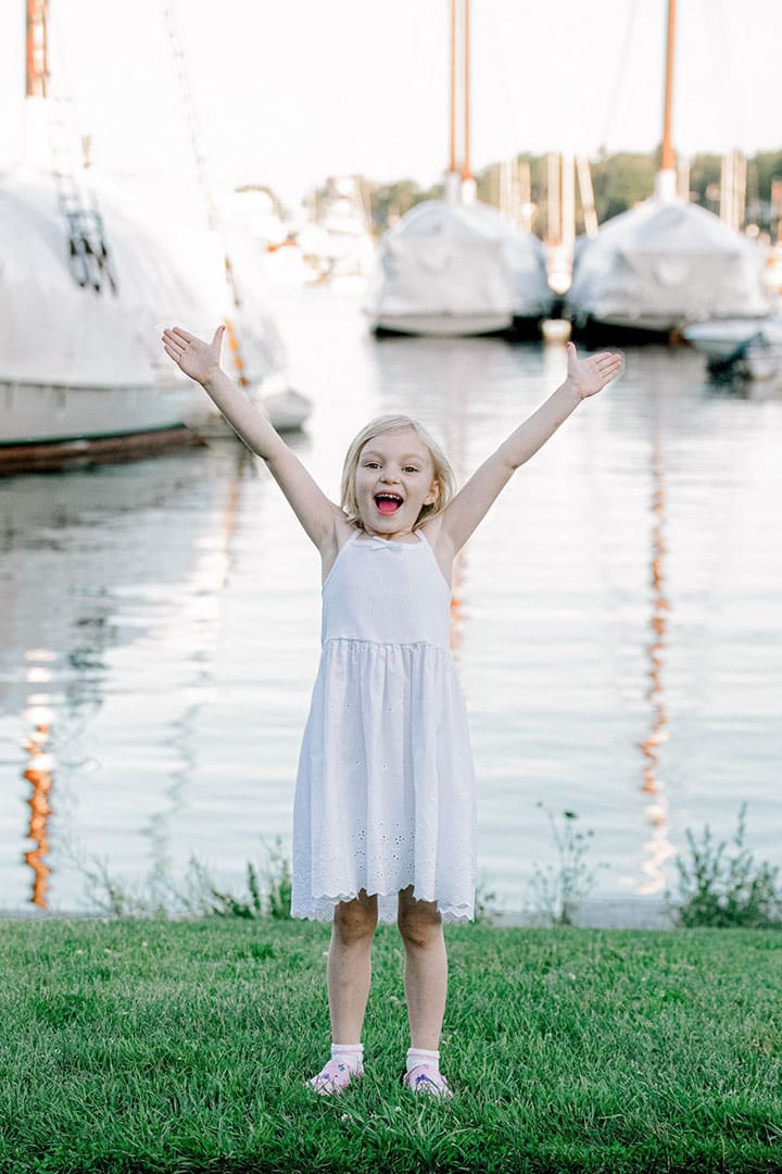 little girl with her hands up in the air in maine