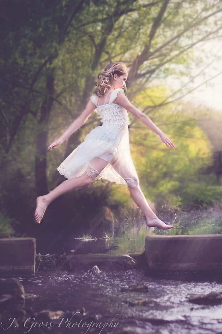 young woman jumping over a broken bridge in maine