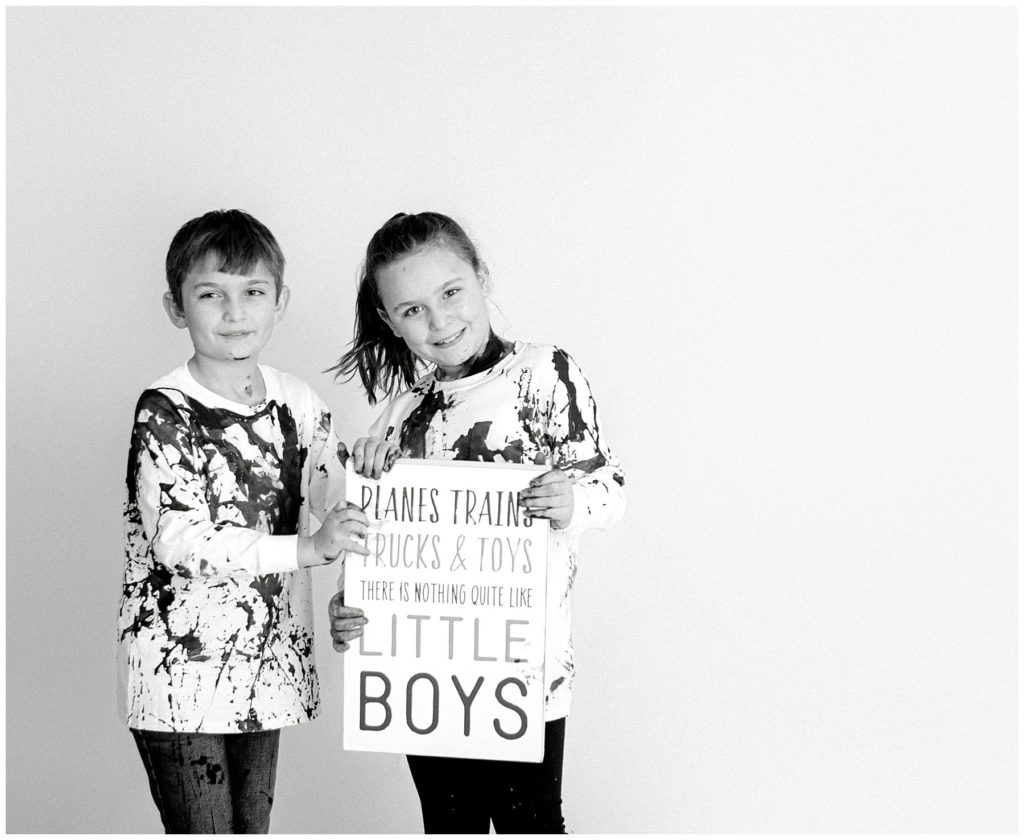 black and white, brother and sister holding sign that baby is a boy