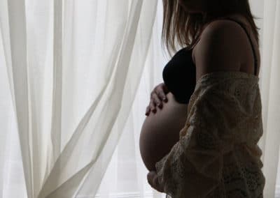 Maine maternity photo of expectant mother looking out window